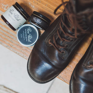 Dark Brown Water Resistant Leather Cream next to Dark Brown Shoe Polish Paste / Wax and Leather Cleaner and Conditioner all beside some brown lace-up Danner Boots