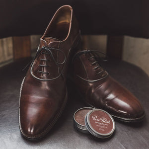 Pair of brown leather oxford shoes polished, next to an open tin of brown Pure Polish
