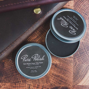 Dark Brown Shoe Polish Paste / Wax used for shining leather boots and shoes by Pure Polish open tin next to a dark brown leather folio