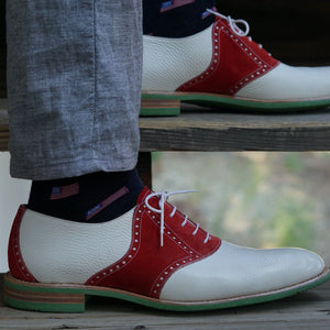 White leather pebble grain saddle shoes worn with grey slacks and American flag socks
