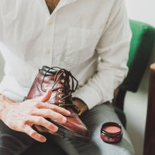 Load image into Gallery viewer, Man applies burgundy cream polish to the toe of a reddish lace up leather boot with his fingertips